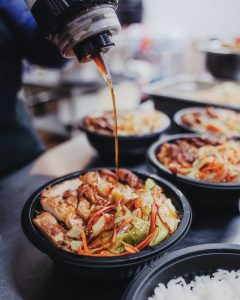 Teriyaki sauce pouring over a chicken bowl